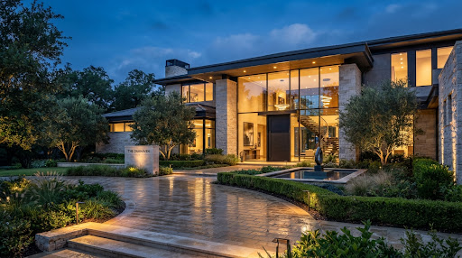 Modern architectural residence at dusk with warm glowing interior and water feature