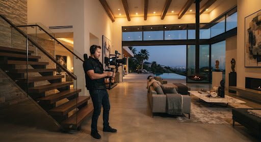 Cinematographer filming architectural details in a contemporary luxury villa at dusk
